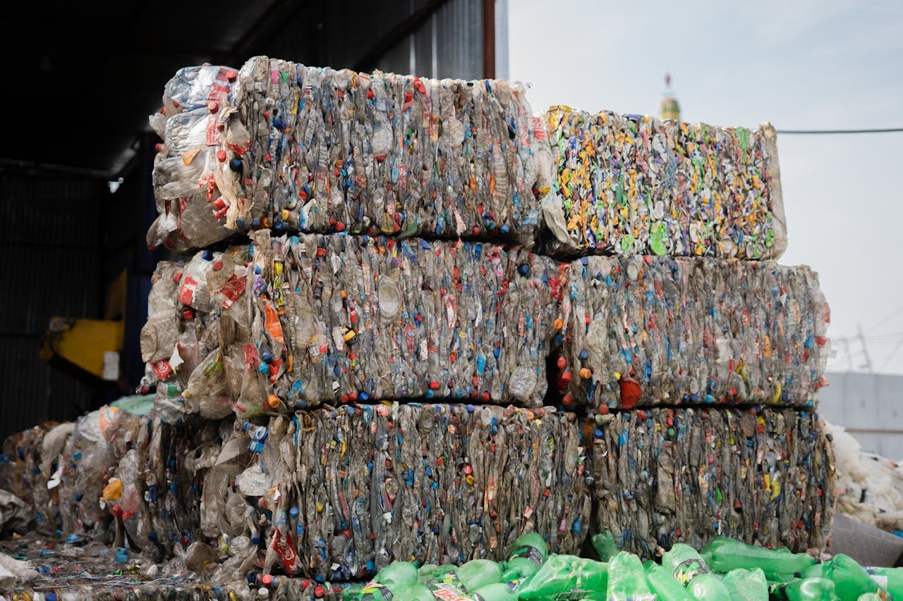 about-us-01 Stacked compressed plastic bottles at a recycling facility, ready for processing.